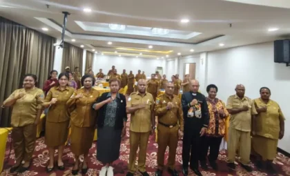 Peserta dan pejabat berseragam dinas berfoto bersama dengan tangan di dada di ruang pertemuan hotel