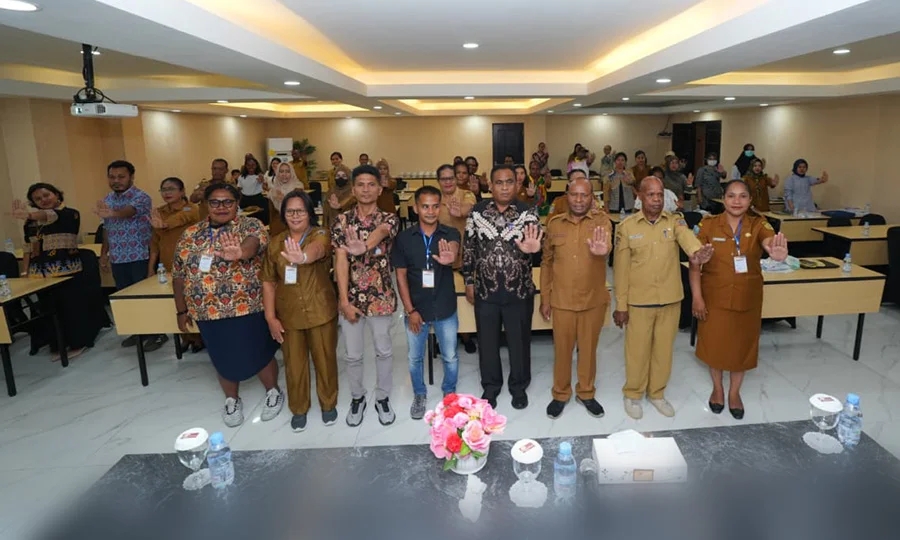 Peserta dan pejabat berfoto bersama sambil mengangkat tangan di ruang pertemuan hotel